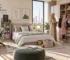 Modern kids rooms design featuring a family organizing clothes in a large wardrobe, a boy studying at a study desk, and a neatly made bed with framed wall art and skyline view in the background.