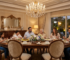 Luxurious classic dining rooms design with a dark walnut dining table, upholstered chairs, ornate gold mirror, crystal chandelier, and a family enjoying dinner غرف سفرة كلاسيك